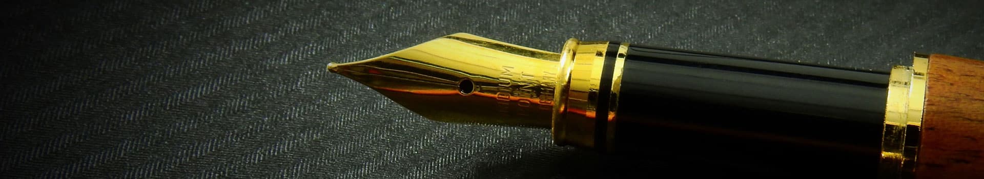 Close-up van een vulpen met gouden penpunt op een donkere ondergrond als symbool voor algemene voorwaarden