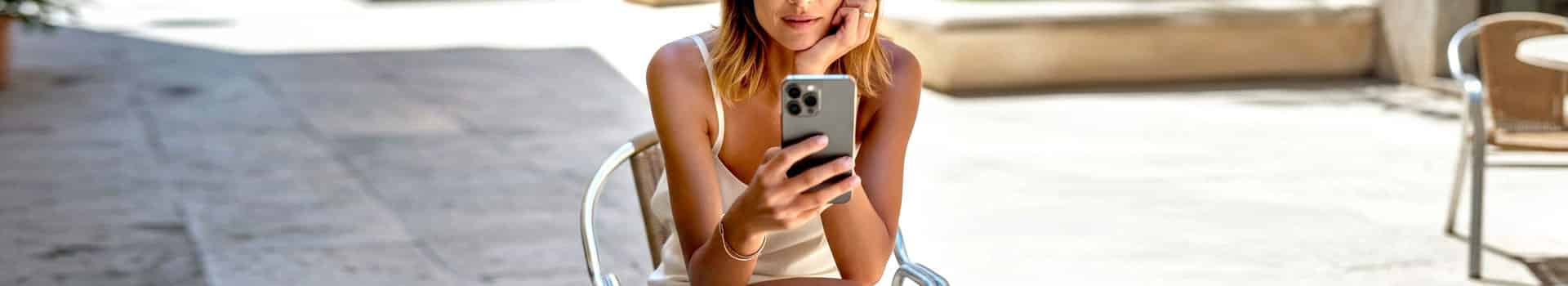 Vrouw bekijkt haar smartphone op een zonnig terras