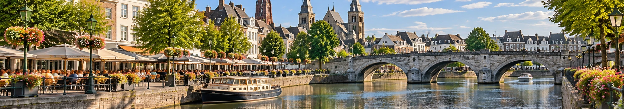 Zonnige sfeer aan de Maas in Maastricht met terrassen en historische brug